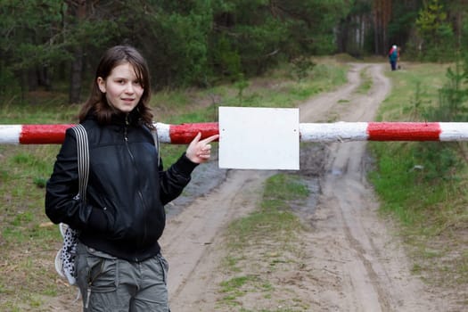 teen girl points to sign on the barrier