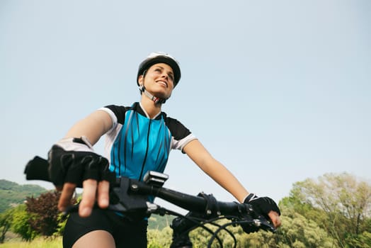 young woman training on mountain bike and cycling in park. Copy space, low angle view
