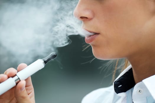 closeup of woman smoking e-cigarette and enjoying smoke. Copy space