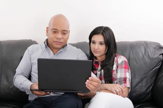 Young couple thinking and looking at a laptop computer