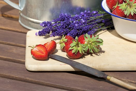 Fresh strawberries lie on a cutting board with a knife
