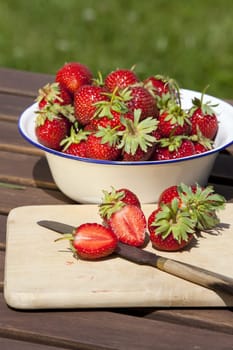 Fresh strawberries In an enamel bowl and on a cutting board with knife