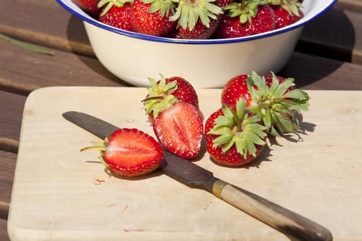 Freshly harvested strawberries on a wooden board with a knife