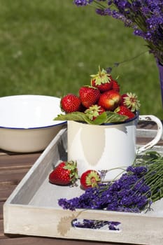 Fresh strawberries and freshly cut lavender lie on a wooden tray
