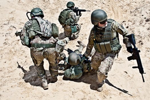 Squad of soldiers evacuate the injured fellow in arms in the desert