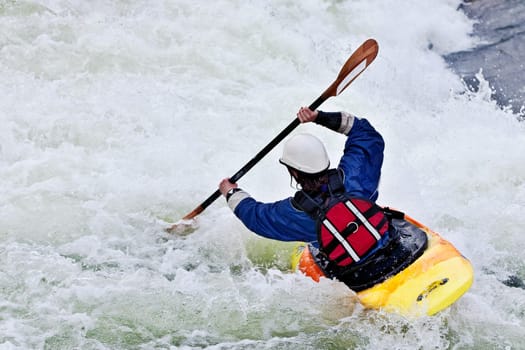 an active female kayaker rolling and surfing in rough water