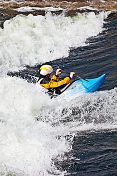 an active male kayaker rolling and surfing in rough water