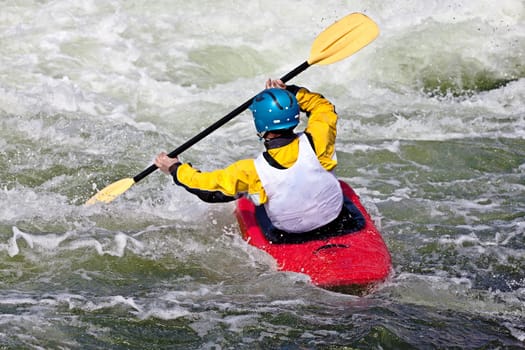 an active male kayaker rolling and surfing in rough water