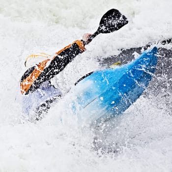 an active male kayaker rolling and surfing in rough water