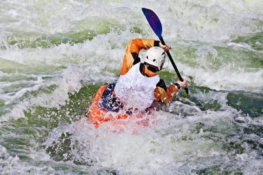 an active male kayaker rolling and surfing in rough water