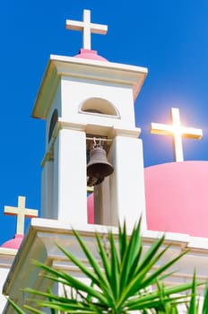 Sun shine reflection in golden crosses on pink domes of Greek Orthodox Church of the Seven Apostles in Capernaum