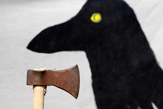 Axe in front of a tent wall painted with a raven