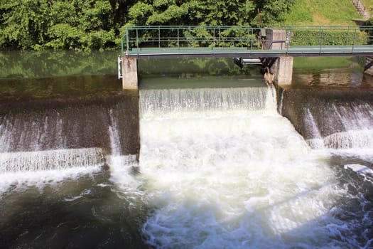 a dam retaining water from a swollen river with its bridge and waterfall