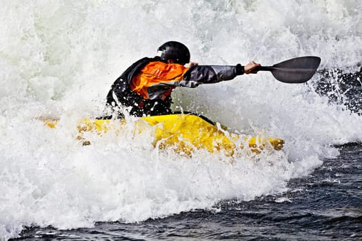 an active male kayaker rolling and surfing in rough water