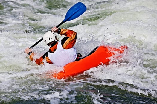 an active male kayaker rolling and surfing in rough water