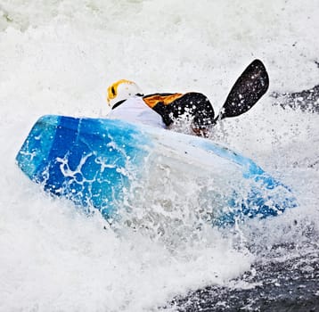 an active male kayaker rolling and surfing in rough water