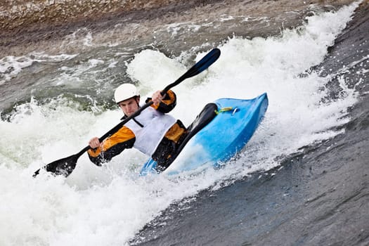 an active male kayaker rolling and surfing in rough water