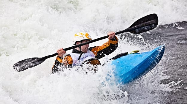 an active male kayaker rolling and surfing in rough water