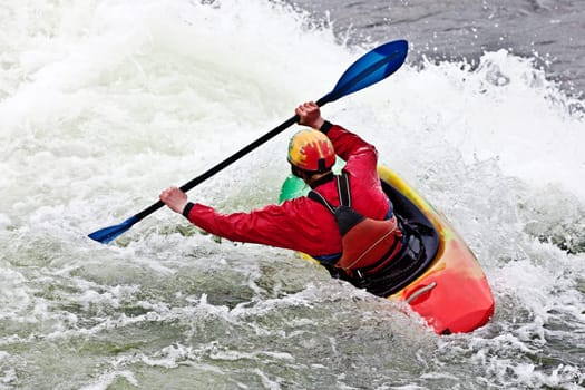 an active male kayaker rolling and surfing in rough water