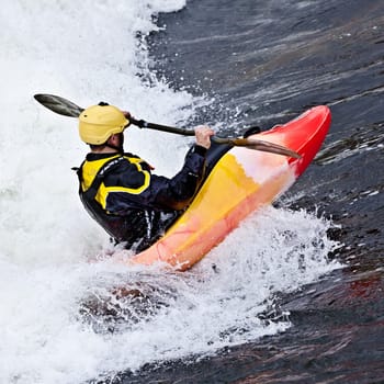 an active male kayaker rolling and surfing in rough water