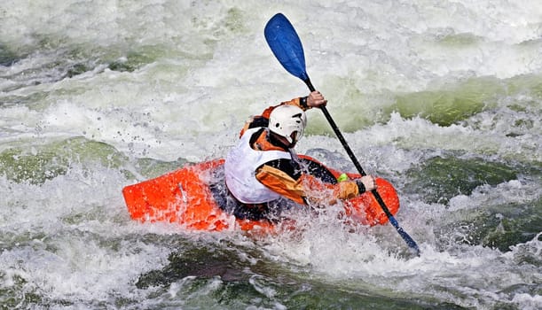 an active male kayaker rolling and surfing in rough water