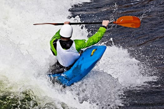 an active male kayaker rolling and surfing in rough water