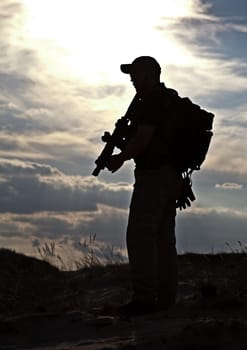 private military contractor with rifle against the sun