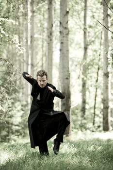 Man with black long coat in the forest