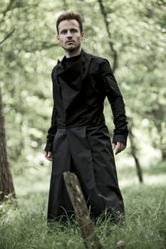 Man with black long coat in the forest