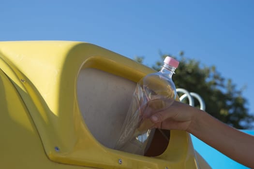 Sorting and recycling household waste. Hand throwing a plastic bottle in the trash.