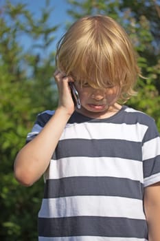 Blond boy is calling outdoors. He got bad news and he is crying.