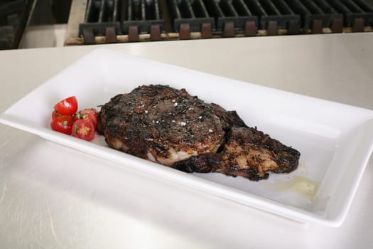 Rib-eye steak resting on the plate in the kitchen ready to serve