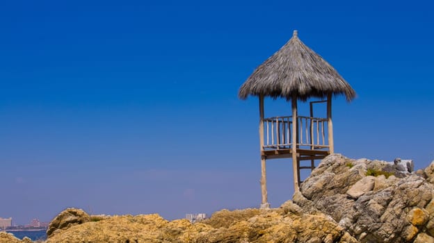 A wooden watch tower standing near a rocky beach.