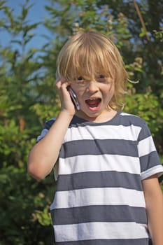 Surprised blond boy in striped shirt is calling