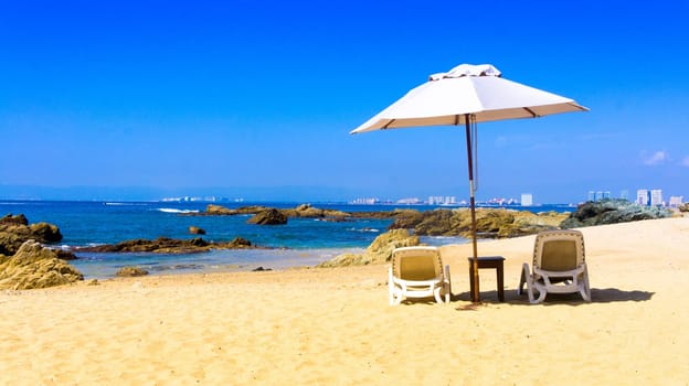 Two chairs a table on a private beach overlooking Puerto Vallarta, Mexico