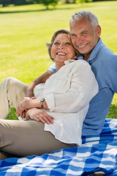 Happy senior couple in the park sitting on blanket