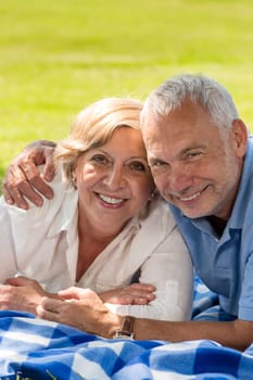Closeup of happy senior couple lying in grass active retirement
