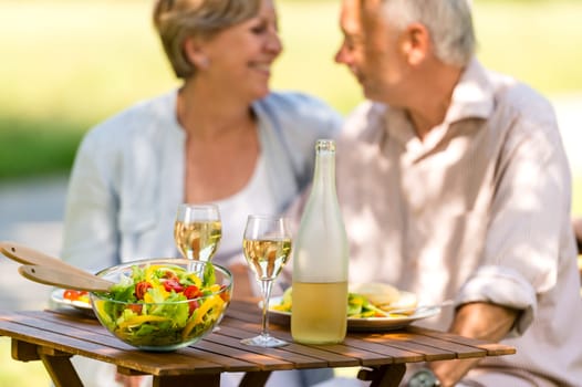 Cheerful senior citizens dating and eating outdoors