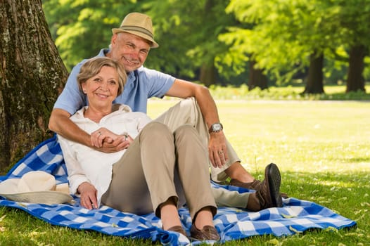 Cheerful pensioners hugging and relaxing outdoors sunny park