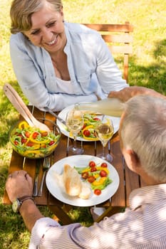 Smiling retired couple eating and drinking outdoors