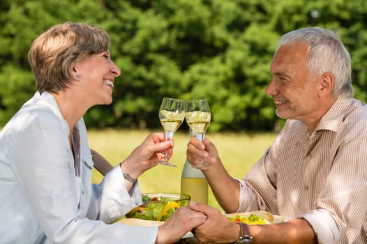 Elderly caucasian couple celebrating outdoors