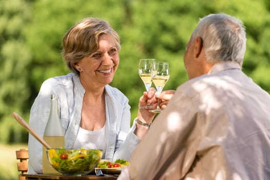Happy senior citizens clinking glasses in garden