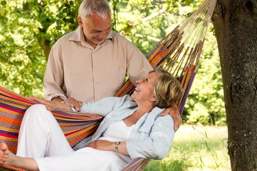 Happy senior couple relax hammock outdoors looking at each other