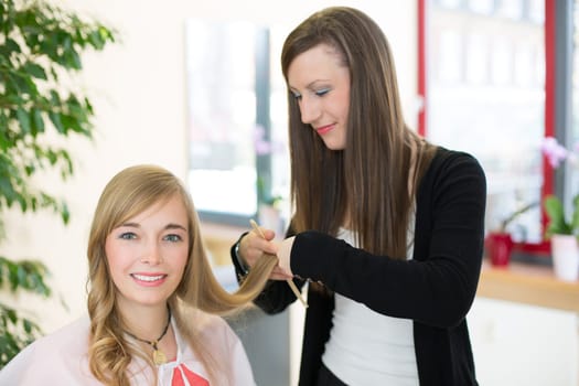 Happy customer getting her hair cut by hairdresser or stylist in salon