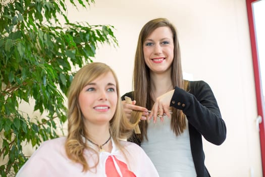 Happy customer getting her hair cut by hairdresser or stylist in salon