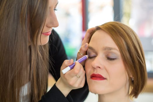 Cosmetician applying eye shadow to customer