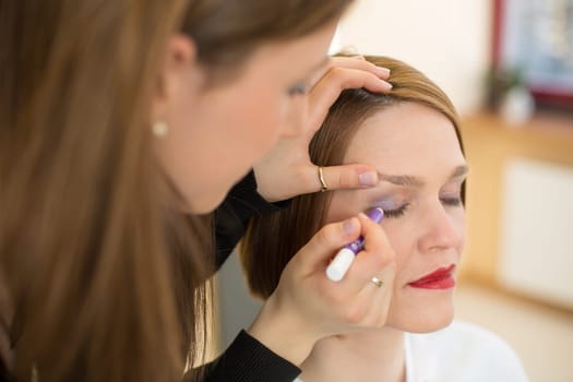 Cosmetician applying eye shadow to customer