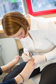 Pedicure at work in salon caring for customers foot nails