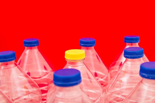 Empty bottles of mineral water, one with a different lid, with a red background