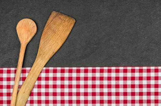 Wooden spoon on a slate plate with a red checkered tablecloth